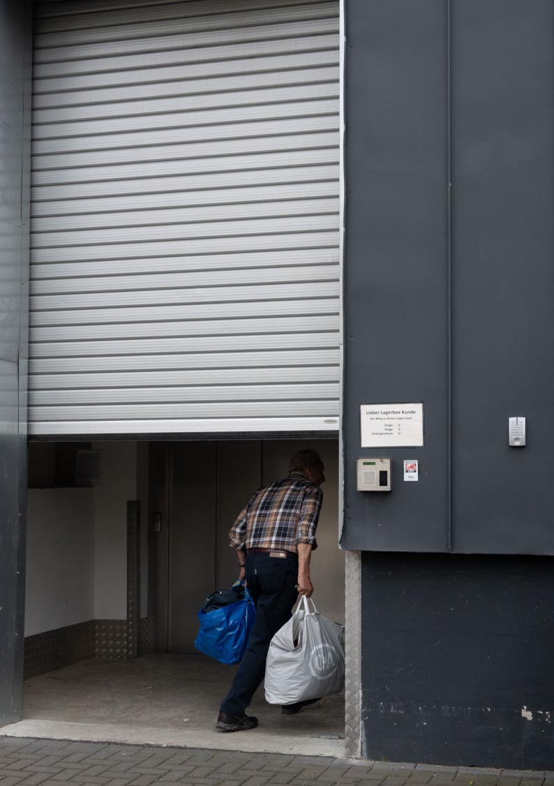 Die Katze trägt zwei Taschen durch ein zum Teil geöffnetes Rolltor