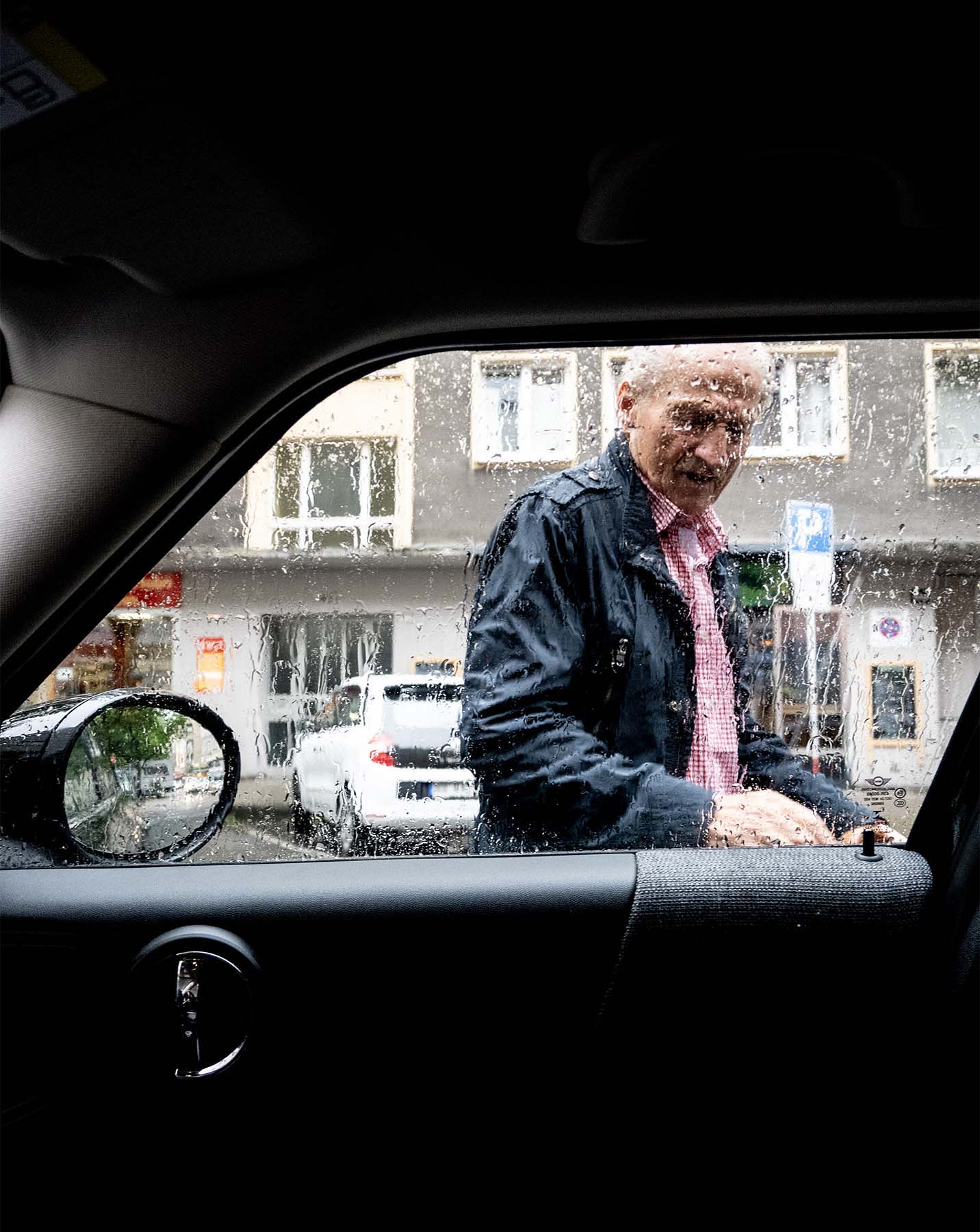 Blick auf die Katze durch ein verregnetes Autofenster.