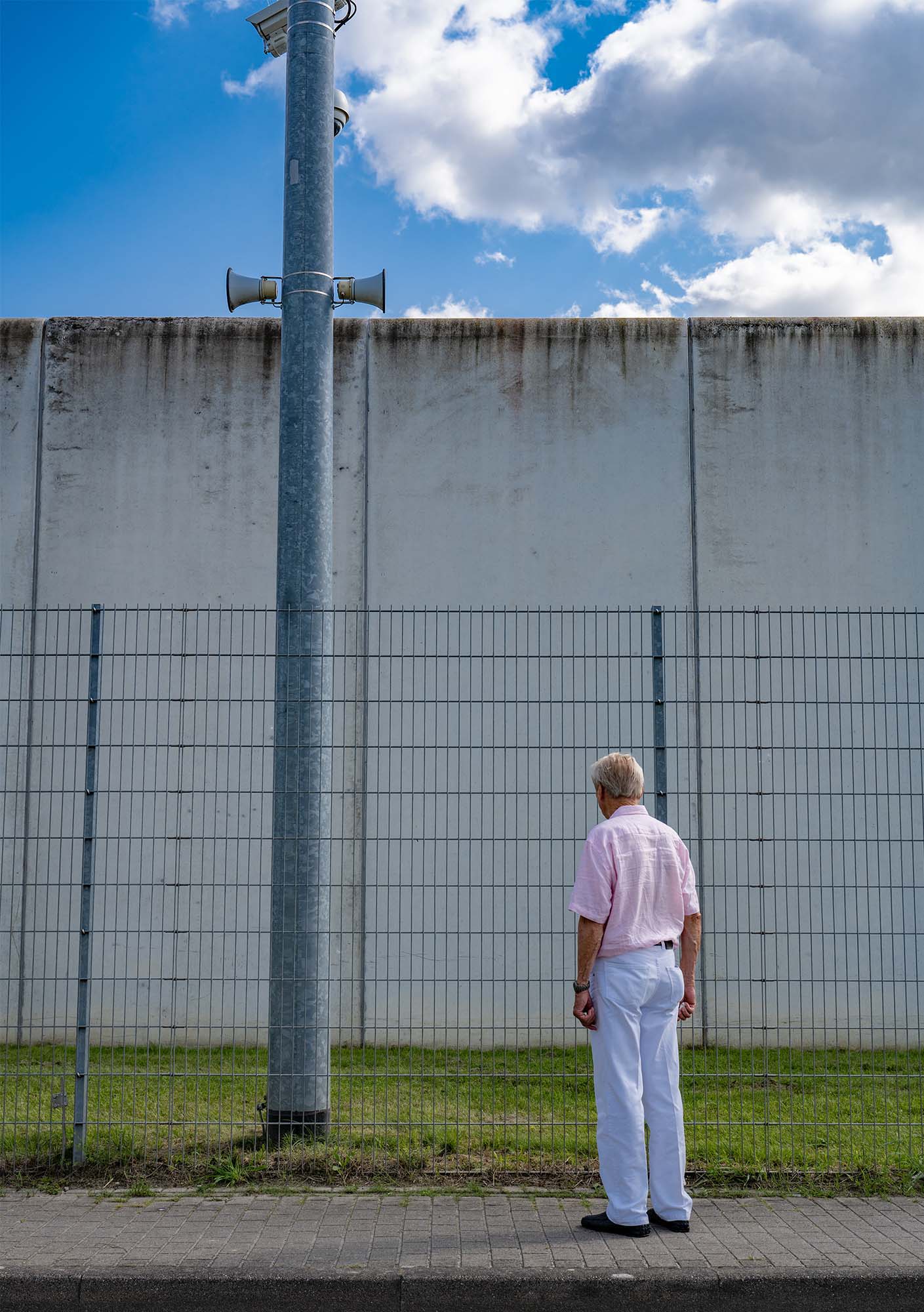 Die Katze steht vor einem Zaun einer JVA