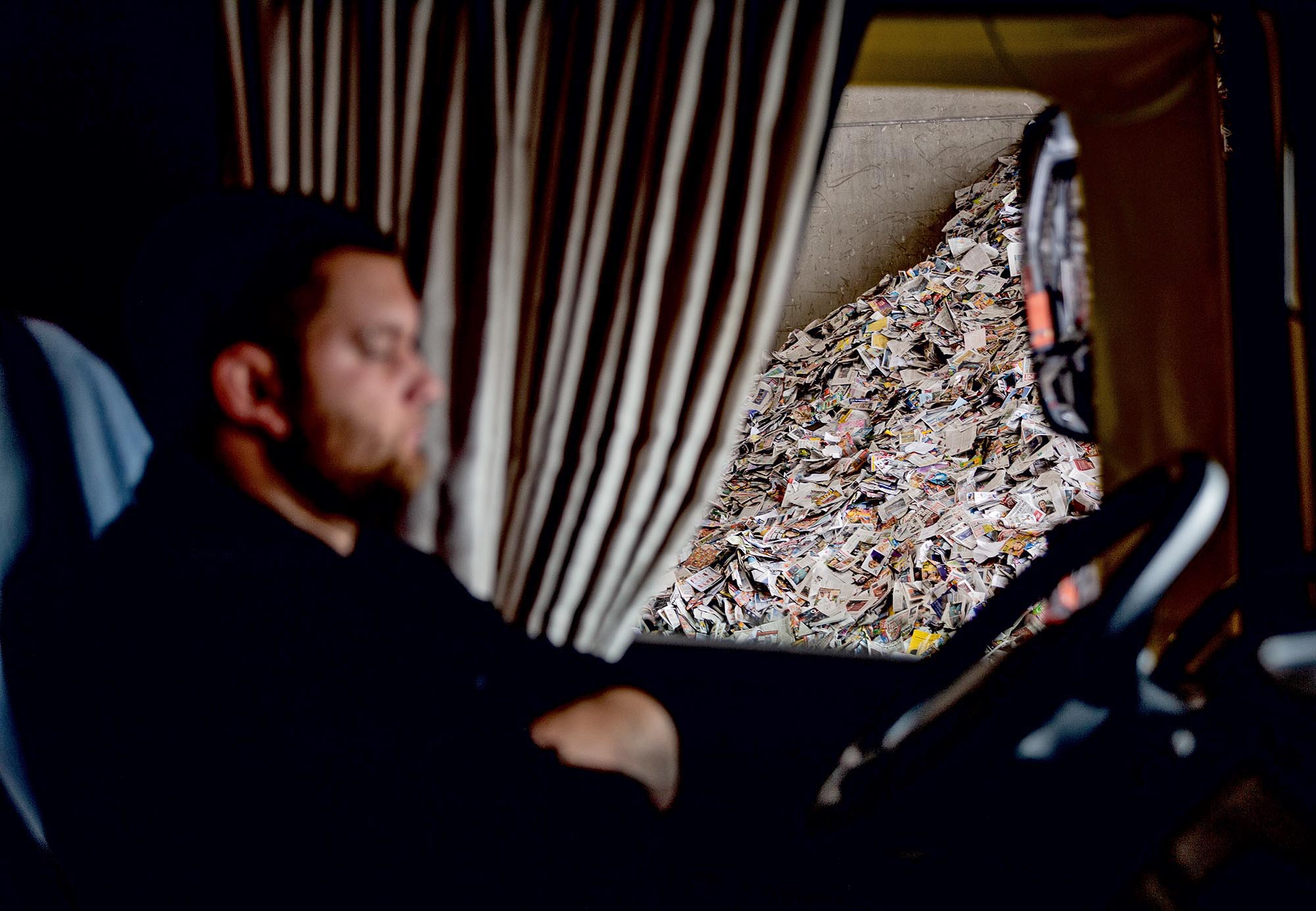 Michl in seiner Fahrerkabine. Aus dem Fenster sieht man einen Haufen Altpapier.