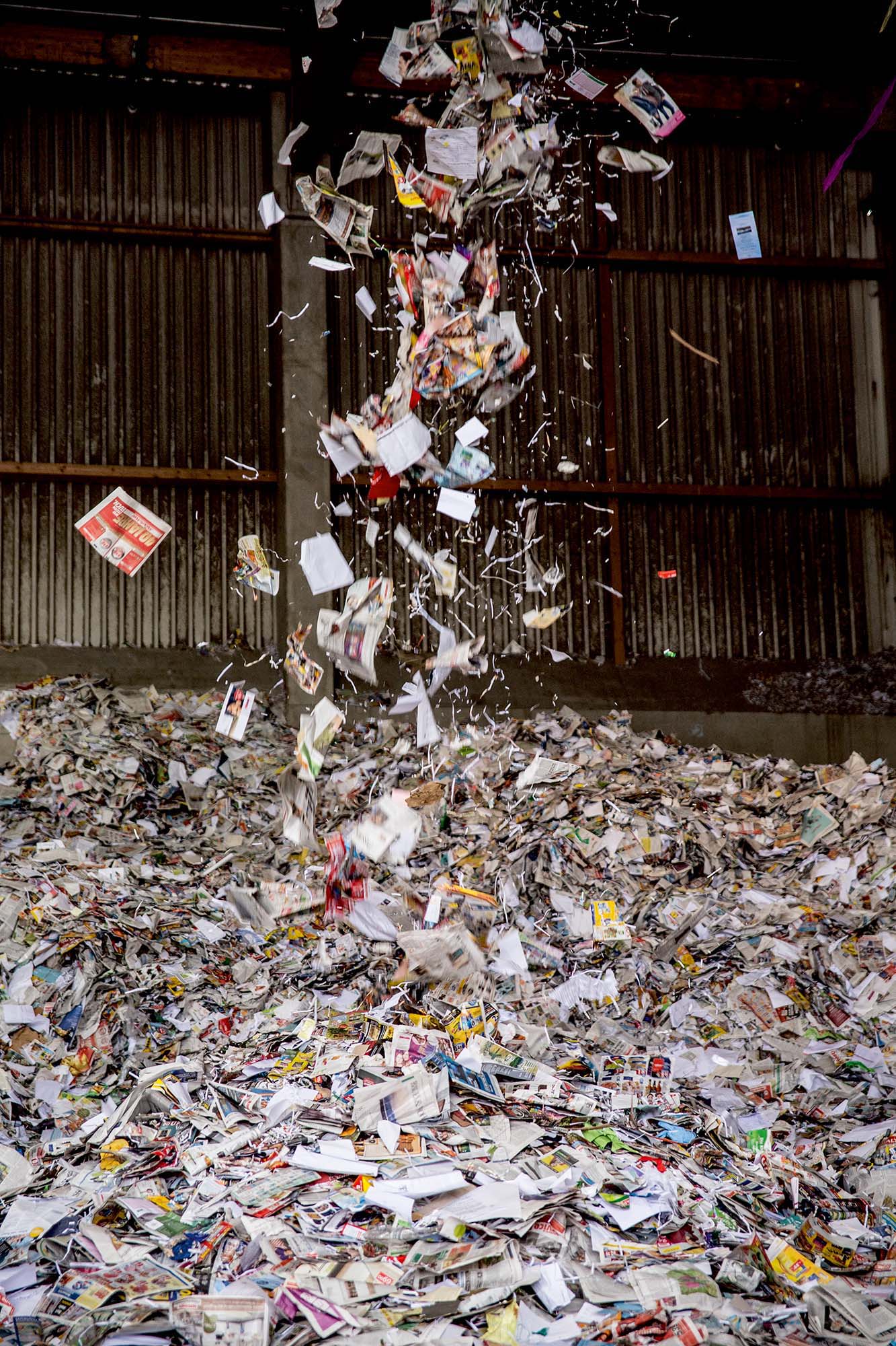 Ein Haufen Altpapier. Vor allem Magazine. Von oben fällt noch weiteres darauf.
