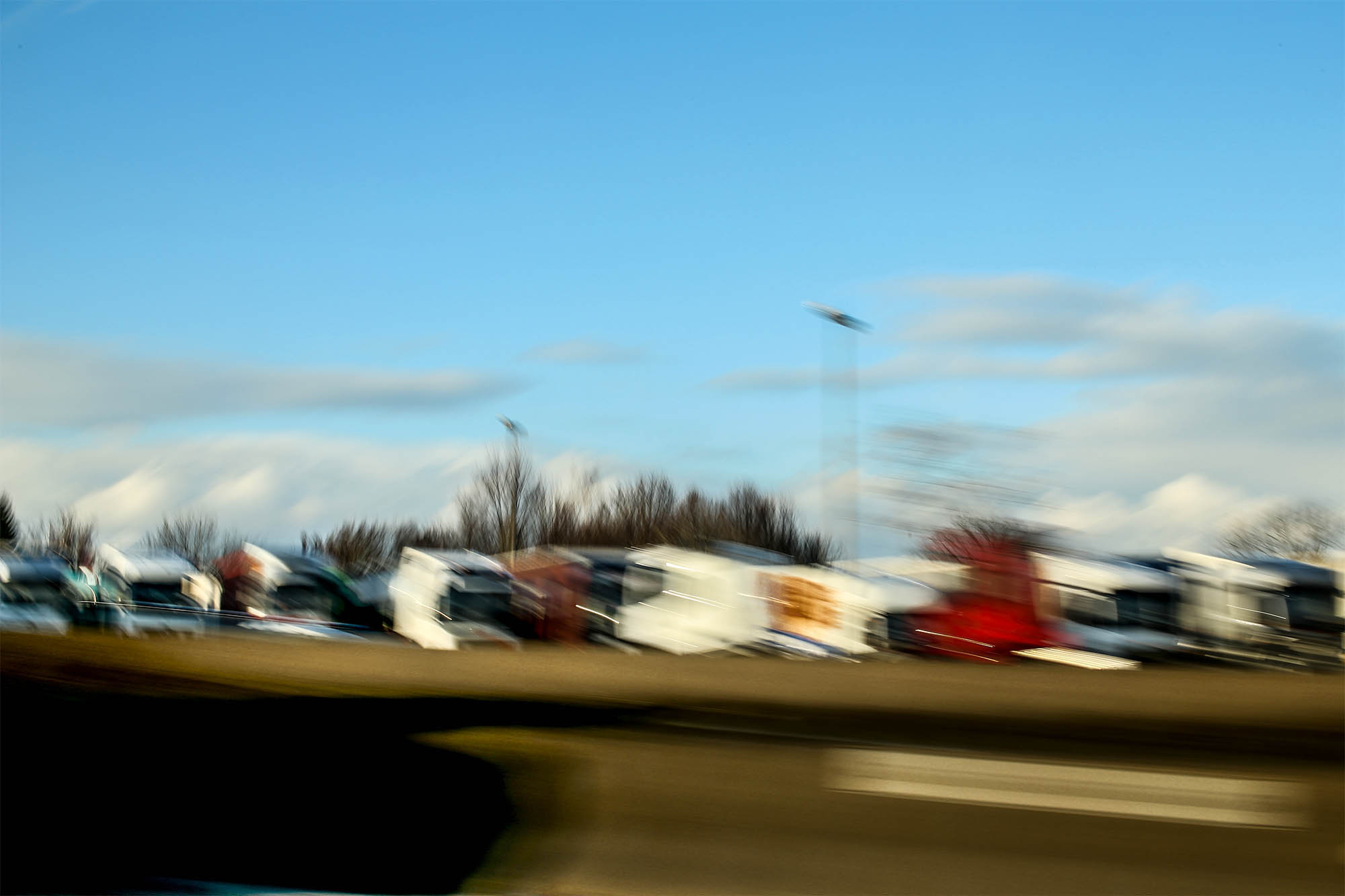 Ein vorüberziehender LKW-Parkplatz neben einer Autobahn